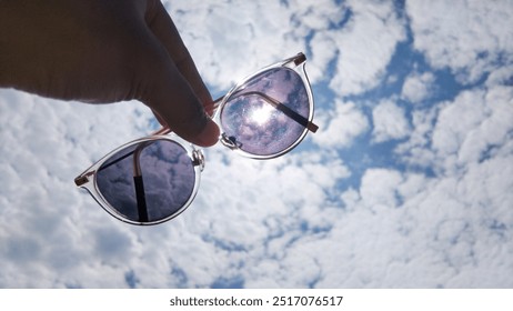 Checking out the sky full of cirrocumulus undulatus clouds, someone's holding photochromic glasses.