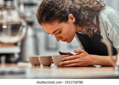 Checking quality. Close up view portrait of a beautiful young woman professional Q Grader test and inspecting the quality of coffee from cup on the table.