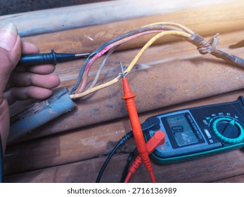 Checking the submersible pump power cable using a multitester.