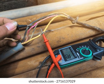 Checking the submersible pump power cable using a multitester.