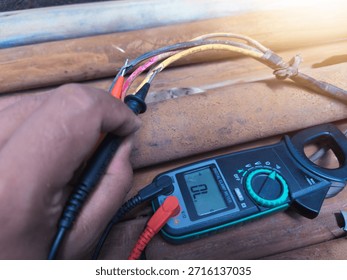 Checking the submersible pump power cable using a multitester.