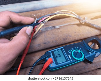Checking the submersible pump power cable using a multitester.