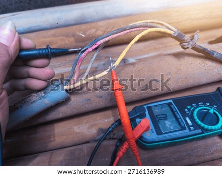 Checking the submersible pump power cable using a multitester.
