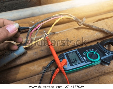 Checking the submersible pump power cable using a multitester.