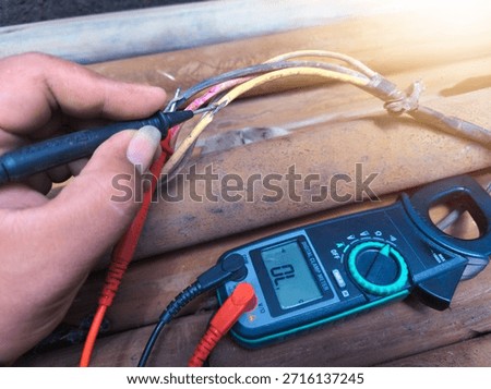 Checking the submersible pump power cable using a multitester.