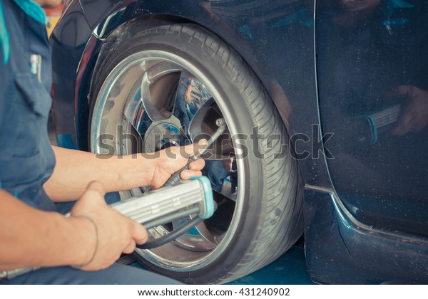 Checking suspension\
and tire pressure in a car by tool electronic tools at  car garage\
, process in vintage\
style