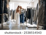 Checking the sweater. Two female friends are in the retail store, choosing clothes, shopping.