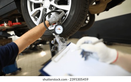 Checking tire pressure by auto mechanic in car repair shop. Tire condition monitoring concept - Powered by Shutterstock