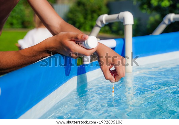 Checking the water quality\
of a pool with the help of a test strip with PH value, chlorine and\
algaecide