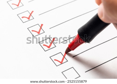 Checklist box with a hand using a red marker pen to check off items