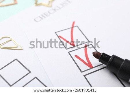 Checklist with marked checkboxes and marker on light blue background, closeup