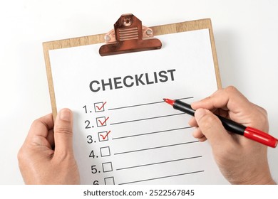 Checklist on the wooden clipboard, hands using a red marker pen to check off items on a white checklist