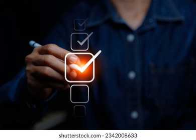 Checklist Online Documentation data Management concept. businessman checking mark on checklist on the check boxes with a red marker on dark background.