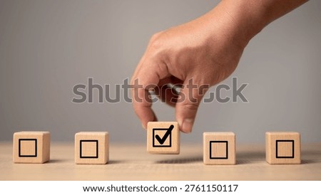Checklist selection concept with hand choosing approved task block symbolizing efficiency, verification and workflow management. Business quality control, productivity improvement.