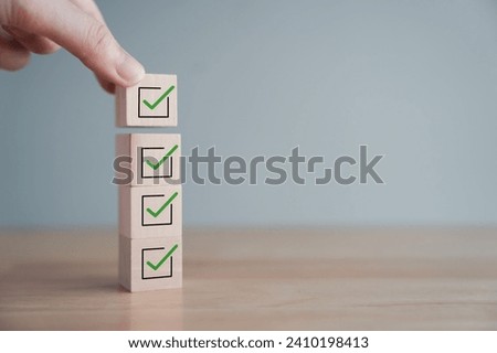 Checklist, Task list, Process success, Solving solution, Mission complete, Survey and assessment, Quality Control, Goal achievement and business success concept. Hand holding check mark on wood block.