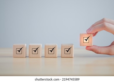 Checklist, Task list, Survey and assessment. Quality Control. Goals achievement and business success. Hand holding Check mark on wooden blocks for complete check list.