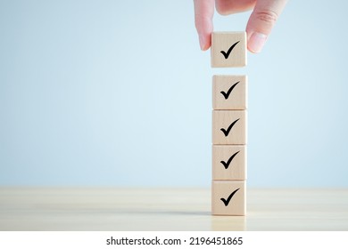 Checklist, Task list, Survey and assessment. Quality Control. Goals achievement and business success. Hand holding Check mark on wooden blocks for complete check list. - Shutterstock ID 2196451865