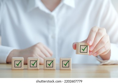 Checklist, Task List, Survey And Assessment, Quality Control, Goals Achievement And Business Success. Elections And Voting, Vote, To Do List, Hand Holding Green Check Mark On Wooden Block.