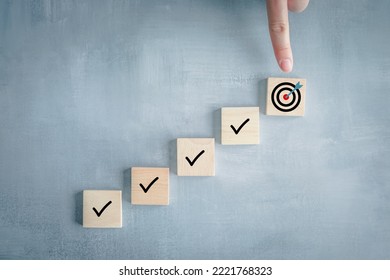 Checklist, Task list, Survey and assessment, Quality Control, Goals achievement and business success. To do list. Hand point to dartboard from top of step of complete with check mark on wooden block.