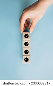 Checklist, Task list, Survey and assessment. Quality Control. Goals achievement and business success. Hand holding Check mark on wooden blocks for complete check list - Shutterstock ID 2300032817