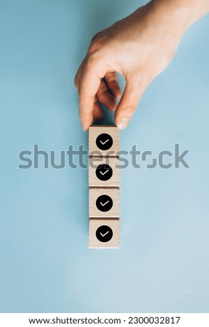 Checklist, Task list, Survey and assessment. Quality Control. Goals achievement and business success. Hand holding Check mark on wooden blocks for complete check list