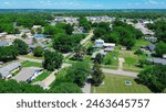 Checotah town of McIntosh County, Oklahoma with suburban residential houses, large backyard, historic downtown Broadway and Main Street background, lush green tree in horizontal line, aerial. USA