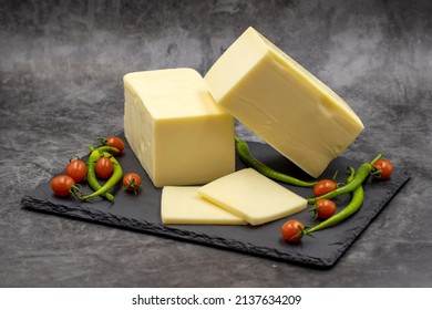 Cheddar Cheese Or Kashkaval Cheese On Dark Background. Cheese Slices On The Serving Board