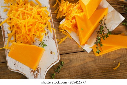 Cheddar Cheese On White Wooden Cutting Board. Top View