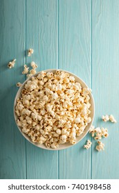 Cheddar Cheese Salted Popcorn In A White Bowl On Light Blue Table Overhead Shot