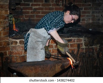 Chedham's Yard, Wellesbourne, Warwickshire/England UK - 06.29.2019: A Female Blacksmith Hammering A Hot Steel Bar On An Anvil.