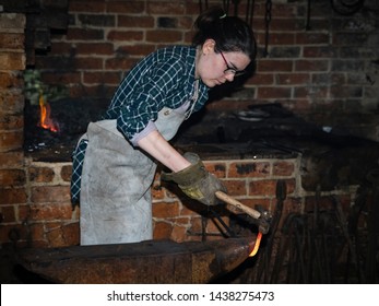 Chedham's Yard, Wellesbourne, Warwickshire/England UK - 06.29.2019: A Female Blacksmith Hammering A Hot Steel Bar On An Anvil.