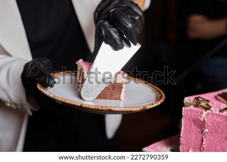 Cheef's hands in black latex gloves cutting chocolate cake