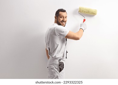 Cheeful house painter using a paint roller and painting a wall