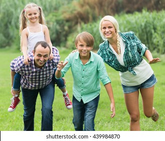 Cheerful active family of four having fun at countryside in summer day  - Shutterstock ID 439984870