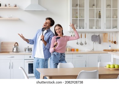 Cheerful Active Millennial European Family Have Fun Together, Singing In Imaginary Microphone, Preparing Food In Kitchen Interior. Positive Mood, Food Blog, Dancing Together At New Home, Copy Space