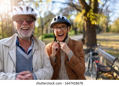 Cheerful active senior couple with bicycle in public park together having fun. Perfect activities for elderly people.