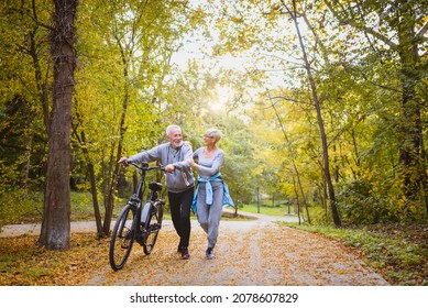 Cheerful active senior couple with bicycles walking through park together. Perfect activities for elderly people. - Powered by Shutterstock