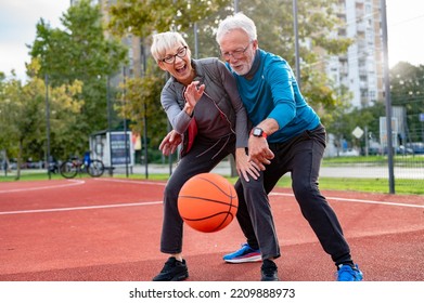 Cheerful active senior couple playing basketball on the urban basketball street court. Happy living after 60. - Powered by Shutterstock