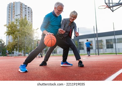 Cheerful active senior couple playing basketball on the urban basketball street court. Happy living after 60. S3niorLife - Powered by Shutterstock