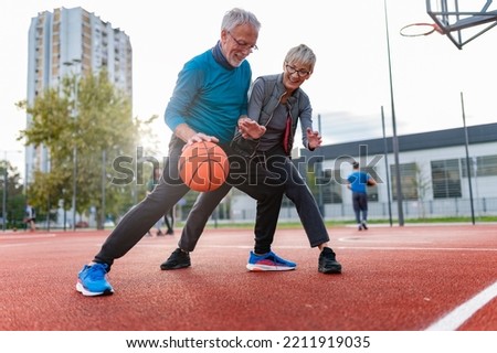 Cheerful active senior couple playing basketball on the urban basketball street court. Happy living after 60. S3niorLife