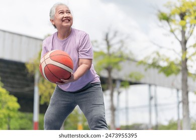 Cheerful active senior woman playing basketball in the urban outdoor basketball court, healthy life concepts - Powered by Shutterstock