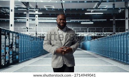 Cheerful admin walking in data center workplace, checking gear for system stability. Jolly IT professional overseeing server hub, configuring racks, optimizing performance, camera A