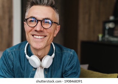 Cheerful Adult Man With Headphones Smiling And Looking At Camera At Home