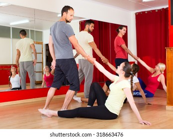 Cheerful Adults Learning How To Dance Tango In Dancing Hall. Men Picking Up Women From Floor