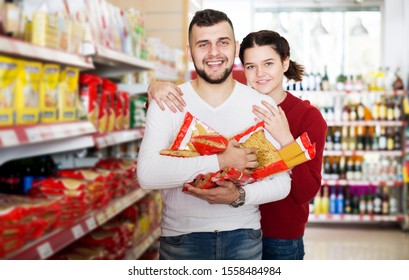 Cheerful Adults Reading Lable Of Pasta At Supermarket