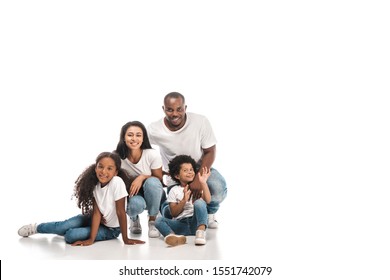 cheerful african american boy waving hand while sitting near parents and sister on white background