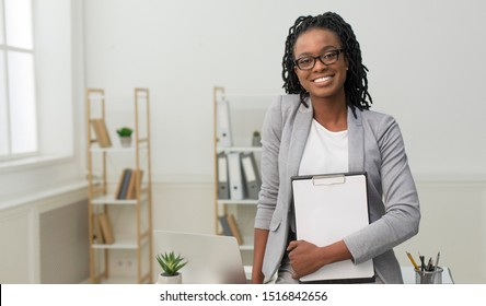 Cheerful African American Business Girl Holding Folder Smiling At Camera Standing In Office. Free Space