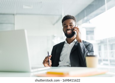 cheerful african american businessman talking on phone in the office