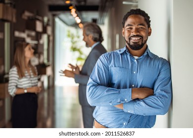 Cheerful African American Executive Businessman At Workspace Office. Portrait Of Smiling Ceo At Modern Office Workplace In Suit Looking At Camera. Happy Leader Standing In Front Of Company Building.