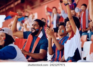 Cheerful African American family celebrating the victory of their favorite team during sports game at the stadium. - Powered by Shutterstock